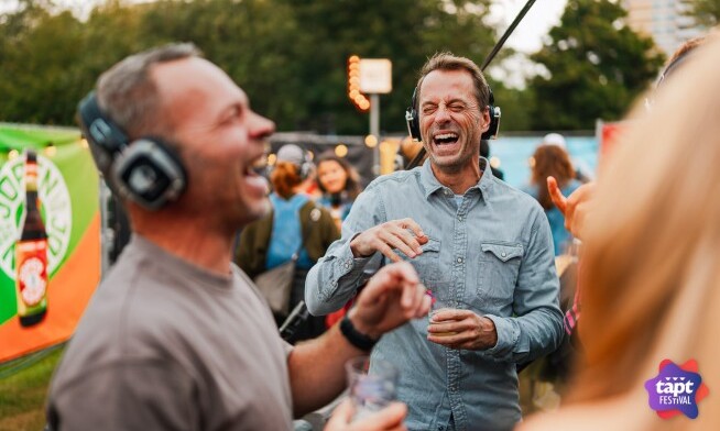 Mensen lachen en dansen met koptelefoons op een festival.