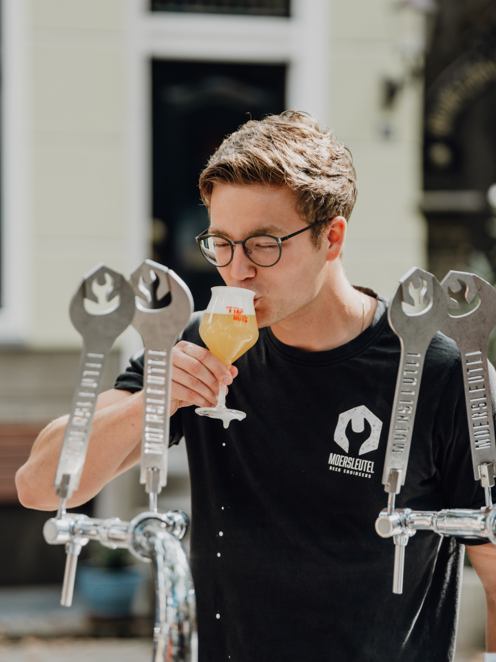 Man drinkt bier van de tap in de buitenlucht, met een Moersleutel T-shirt aan.