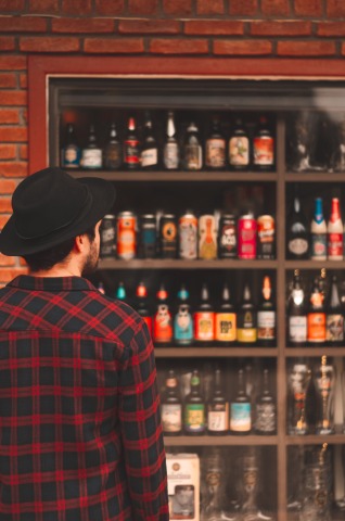 Man kijkt naar een kast vol met bierflesjes en glazen