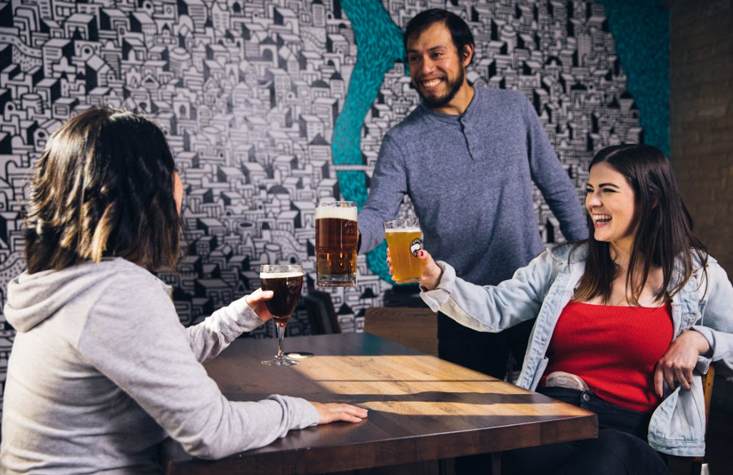 Drie mensen proosten in een bar met bier