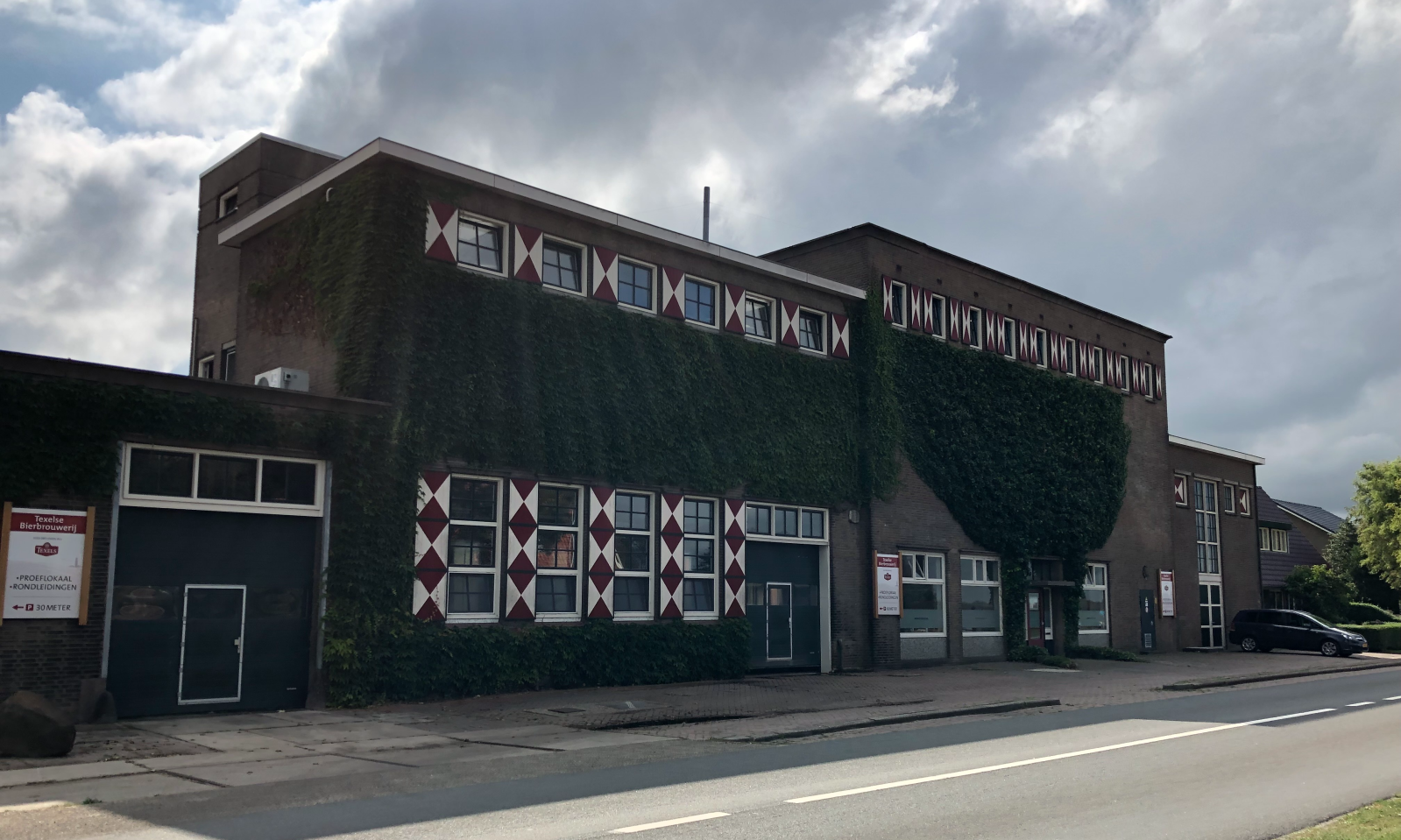 Buitenaanzicht van de Texelse Bierbrouwerij met groene klimop en karakteristieke luiken.