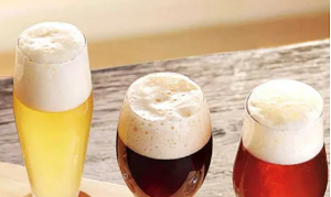 Drie glazen bier op een houten tafel met schuimkraag.