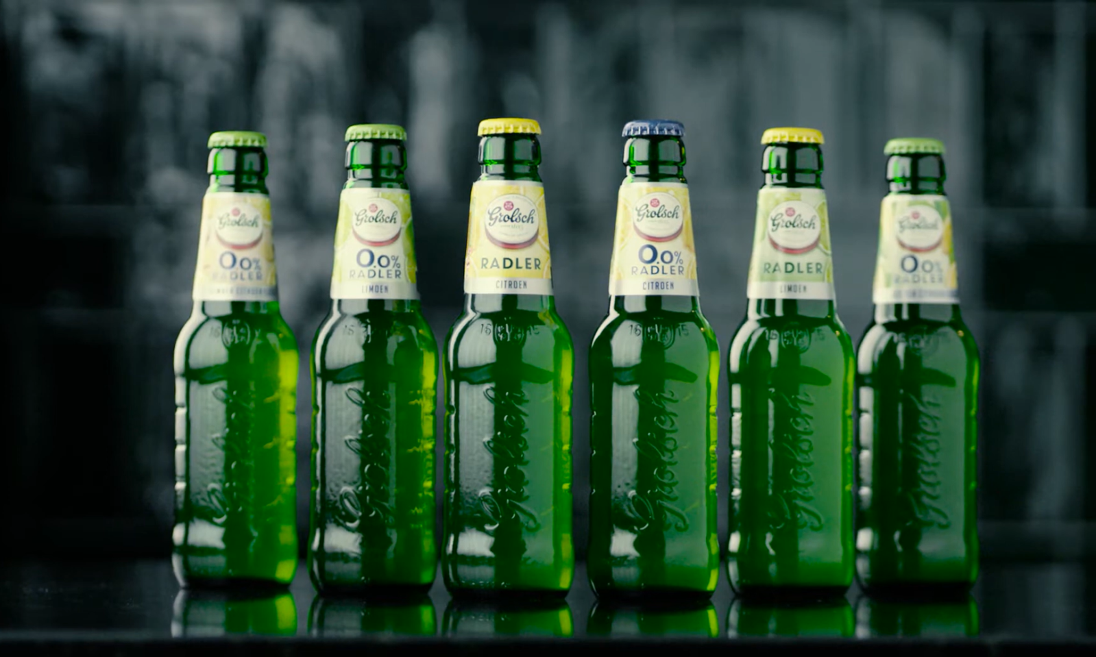 Zes Grolsch Radler flesjes naast elkaar op een zwarte achtergrond.