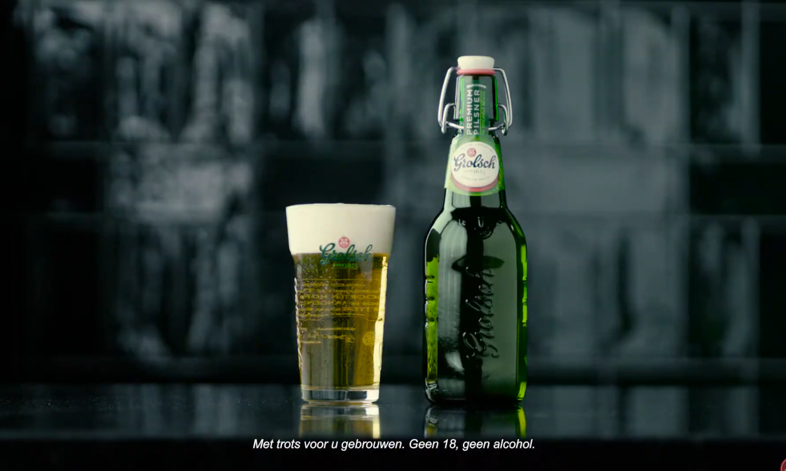 Grolsch Premium Pilsener fles en glas bier op donkere achtergrond.