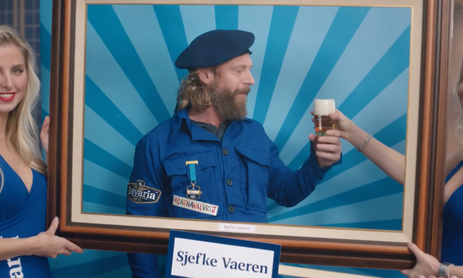 Drie mensen met een houten lijst, man in blauw uniform houdt bierglas vast.
