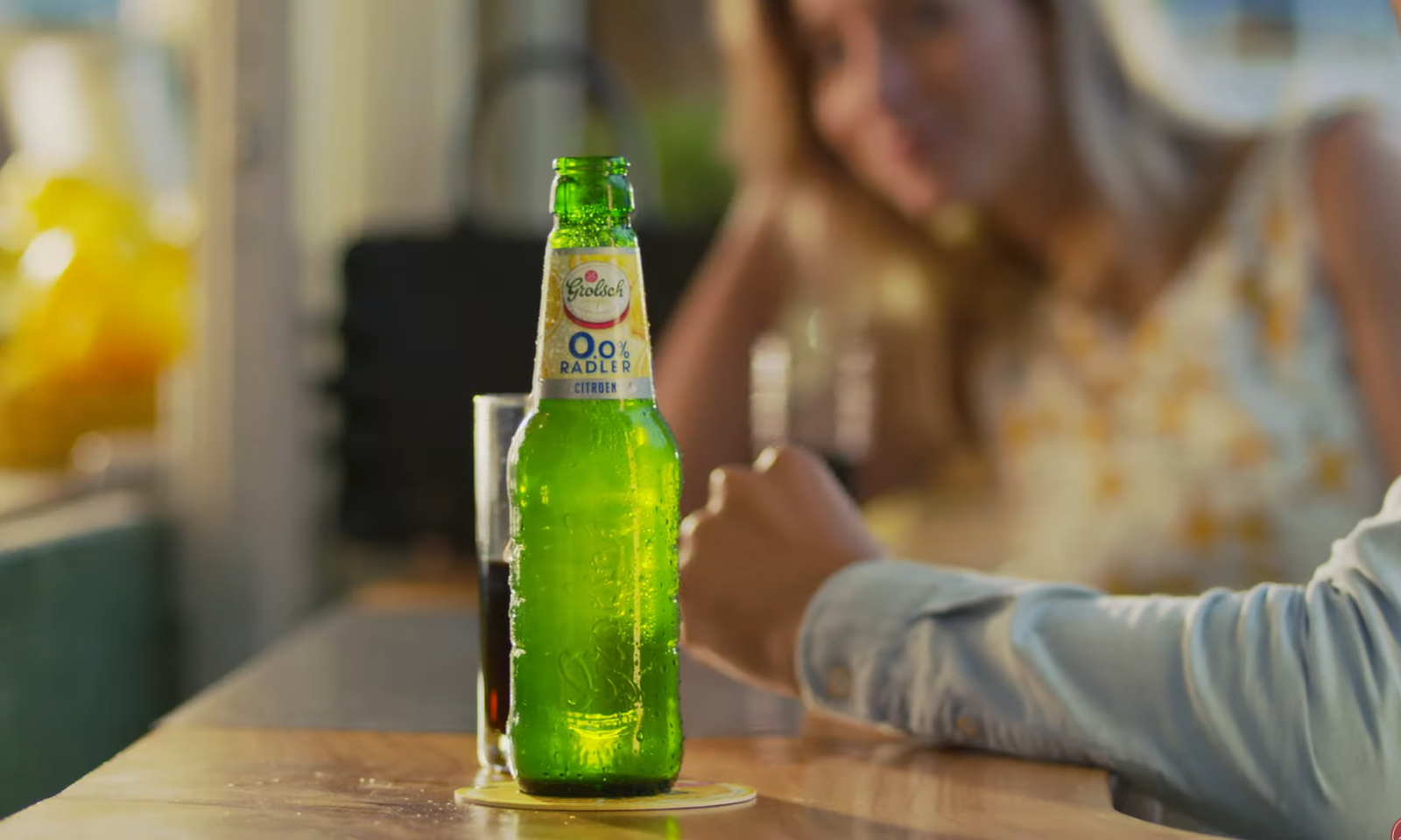 Groene fles Grolsch 0,0% Radler Citroen op tafel met wazige achtergrond.