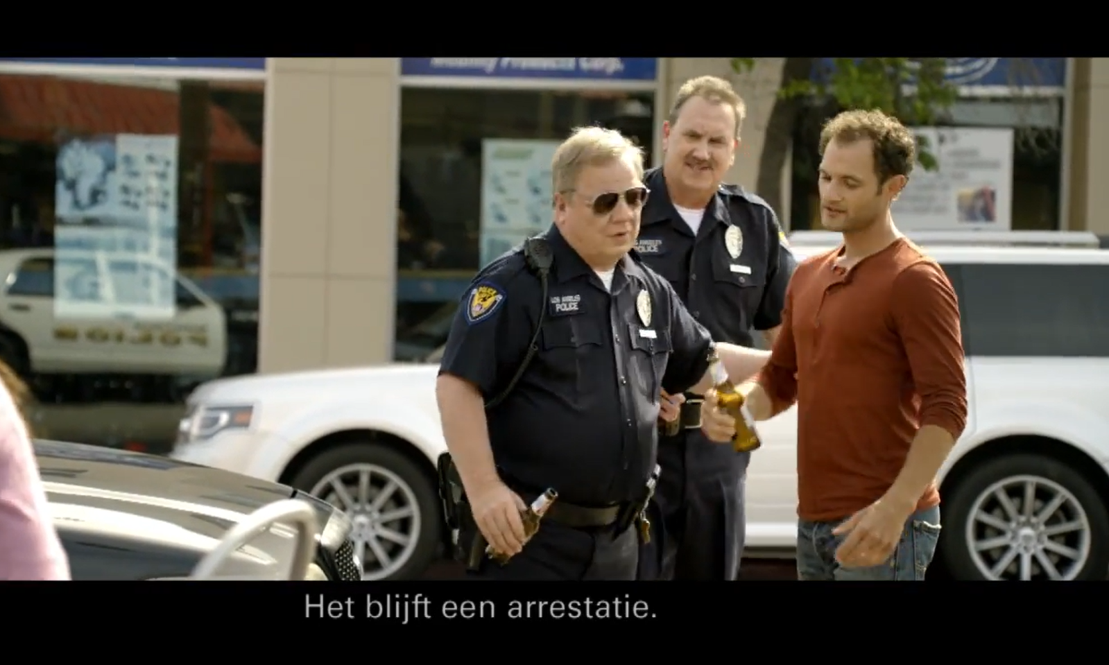 Twee politieagenten praten met een man met een Bavaria 0.0% flesje in zijn hand.