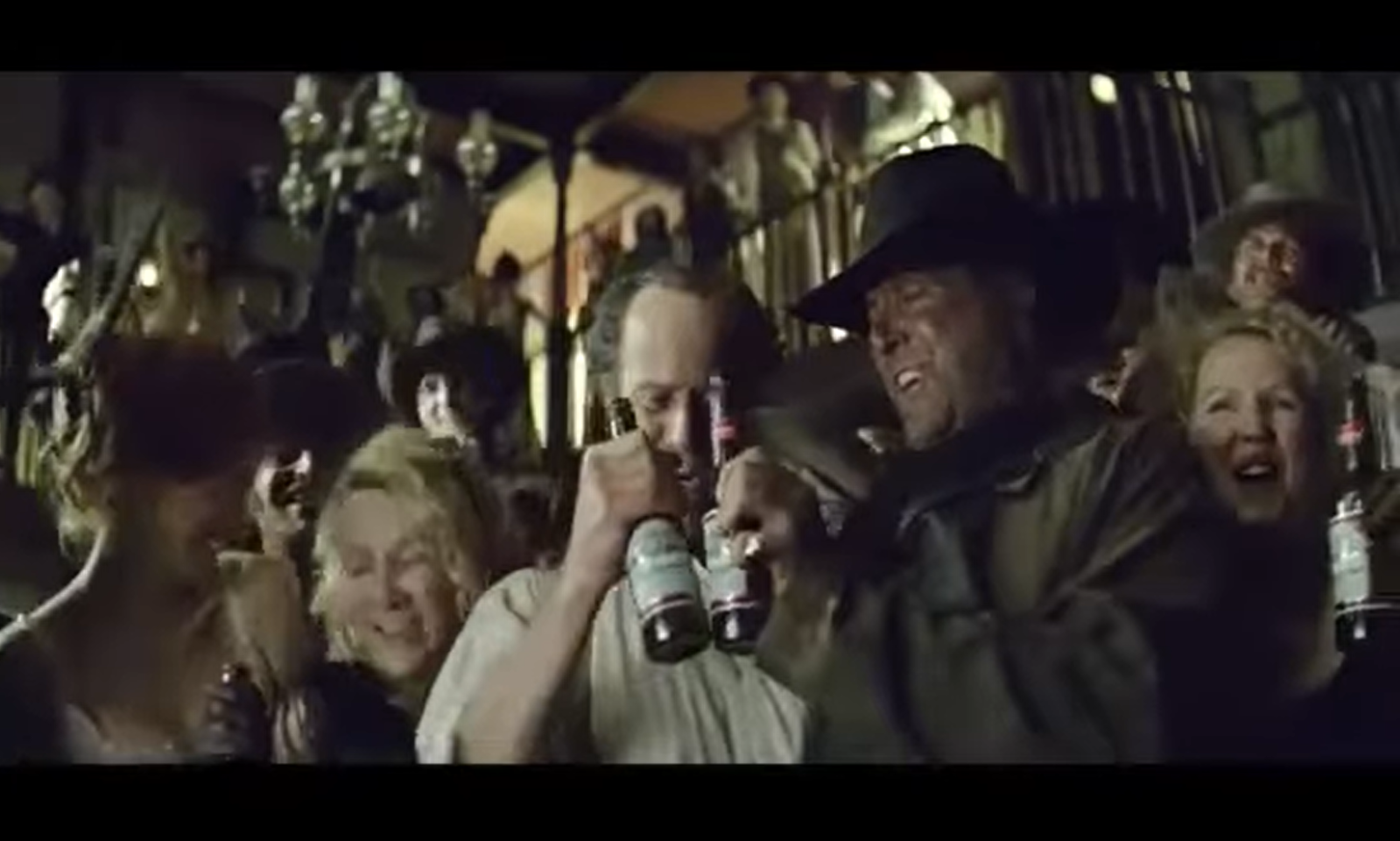 Mensen in een drukke saloon met flessen bier en een vreugdevolle sfeer.