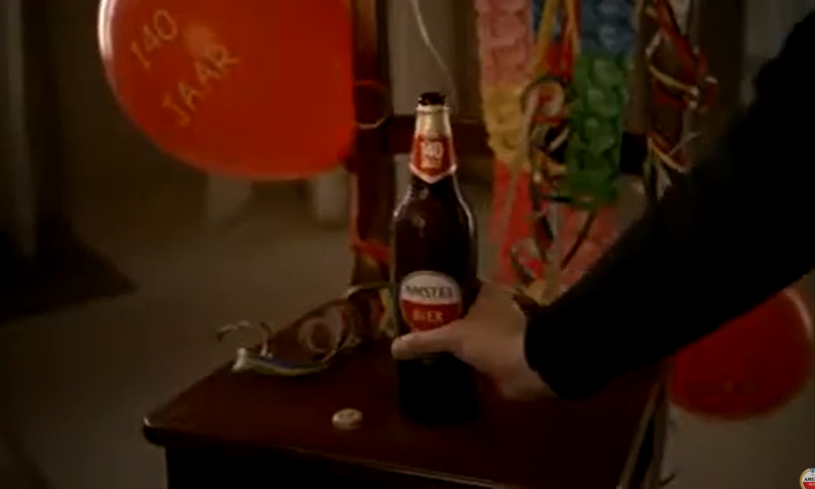 Fles Amstel bier naast rode ballon met 